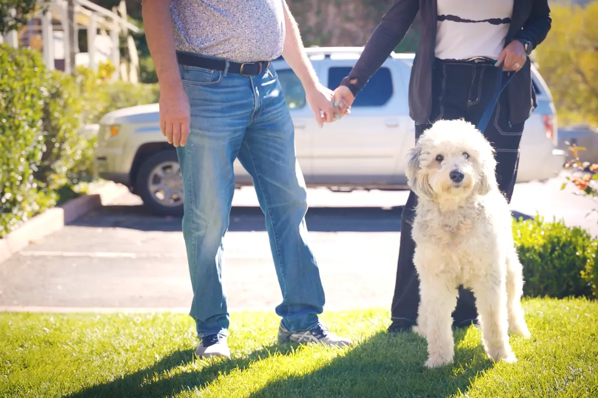 pet-friendly-hotels-prescott-az-dog-getaway Couple standing outdoors with a white dog on a leash at a pet-friendly hotel in Prescott, Arizona.